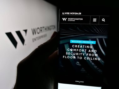 Stuttgart, Almanya - 07-06-2024: ABD 'li metal işleme şirketi Worthington Enterprises Inc.' in logolu web sitesi ile cep telefonu tutan kişi. Telefon ekranının merkezine odaklan.