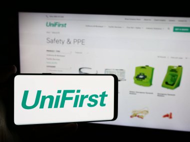Stuttgart, Almanya - 07-06-2024: Üzerinde ABD 'li koruyucu giysi şirketi UniFirst Corporation' ın logosu bulunan cep telefonu web sayfasının önünde duruyor. Telefon ekranına odaklan.