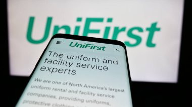 Stuttgart, Almanya - 07-06-2024: ABD 'li koruyucu giyim şirketi UniFirst Corporation' ın web sayfası ile ticaret logosu önünde akıllı telefon. Telefon ekranının sol üst kısmına odaklan.