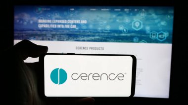 Stuttgart, Almanya - 07-06-2024: ABD 'li otomotiv yazılım şirketi Cerence Inc.' in logosuyla cep telefonu sahibi kişi iş sayfasının önünde. Telefon ekranına odaklan.