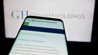 Stuttgart, Almanya - 07-08-2024: İş logosu önünde ABD 'li medya şirketi Graham Holding Company' nin web sitesi ile cep telefonu. Telefon ekranının sol üst kısmına odaklan.
