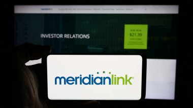 Stuttgart, Almanya - 07-08-2024: ABD 'li finans yazılım şirketi MeridianLink Inc.' in logosuyla cep telefonu sahibi kişi iş sayfasının önünde. Telefon ekranına odaklan.