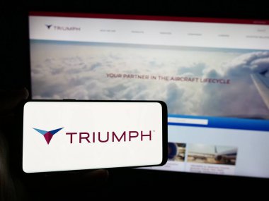 Stuttgart, Almanya - 07-08-2024: İnternet sitesi önünde ABD 'li havacılık şirketi Triumph Group Inc.' in logosuna sahip kişi. Telefon ekranına odaklan.