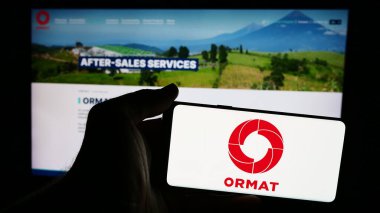 Stuttgart, Germany - 07-08-2024: Person holding cellphone with logo of geothermal energy company Ormat Technologies Inc. in front of business webpage. Focus on phone display. clipart