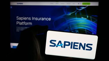 Stuttgart, Germany - 07-08-2024: Person holding smartphone with logo of Israeli company Sapiens International Corporation N.V. in front of website. Focus on phone display. clipart