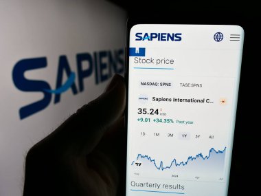 Stuttgart, Almanya - 07-08-2024: İsrailli şirket Sapiens International Corporation N.V. 'nin logolu web sitesi ile cep telefonu tutan kişi. Telefon ekranının merkezine odaklan.