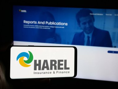 Stuttgart, Almanya - 07-08-2024: İnternet sitesi önünde Harel Sigorta Yatırımları ve Mali Hizmetler Ltd. logosuna sahip akıllı telefon sahibi kişi. Telefon ekranına odaklan.