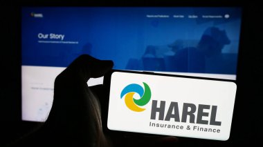 Stuttgart, Almanya - 07-08-2024: İnternet sayfası önünde Harel Sigorta Yatırımları ve Mali Hizmetler Ltd. 'nin logosuna sahip cep telefonu sahibi kişi. Telefon ekranına odaklan.