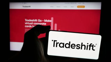 Stuttgart, Almanya - 07-10-2024: Web sitesi önünde ABD 'li B2B ağ şirketi Tradeshift Holding Inc.' nin logosuna sahip kişi. Telefon ekranına odaklan.