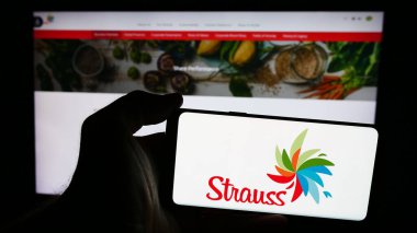 Stuttgart, Almanya - 07-10-2024: İsrailli tüketici malları şirketi Strauss Group Ltd. 'nin logosuna sahip akıllı telefon sahibi kişi web sitesinin önünde. Telefon ekranına odaklan.