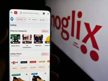 Stuttgart, Almanya - 07-11-2024: E-ticaret şirketi Mogli Labs 'in (Hindistan) internet sayfası ile akıllı telefon tutan kişi Ltd. Logolu Ltd. Telefon ekranının merkezine odaklan.