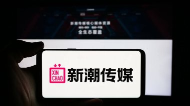 Stuttgart, Almanya - 07-11-2024: Reklam şirketi Chengdu Xinchao Media Group Co. Ltd. nin logosuyla cep telefonu sahibi kişi web sayfasının önünde. Telefon ekranına odaklan.