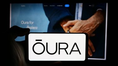 Stuttgart, Almanya - 07-11-2024: Finlandiya sağlık teknolojisi şirketi Oura Health Oy 'un logosuyla cep telefonu tutan kişi iş sayfasının önünde. Telefon ekranına odaklan.