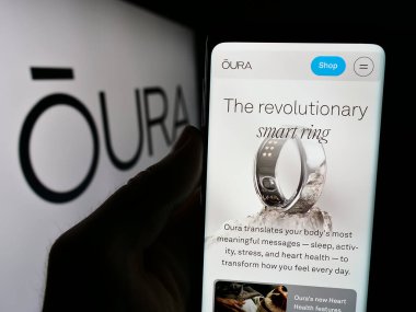 Stuttgart, Almanya - 07-11-2024: Finlandiya sağlık teknolojileri şirketi Oura Health Oy 'un logo önündeki internet sayfası ile cep telefonu tutan kişi. Telefon ekranının merkezine odaklan.