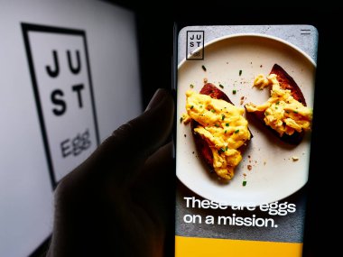Stuttgart, Almanya - 07-11-2024: ABD 'li gıda teknolojisi şirketi Eat Just Inc.' in internet sayfası ile cep telefonu tutan kişi logonun önünde. Telefon ekranının merkezine odaklan.