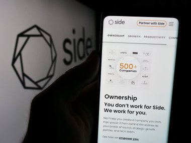 Stuttgart, Almanya - 07-12-2024: ABD 'li emlak komisyoncusu Side Real Estate Inc.' in web sayfası ile logo önünde cep telefonu tutan kişi. Telefon ekranının merkezine odaklan.