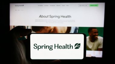 Stuttgart, Almanya - 07-12-2024: İş sayfası önünde ABD 'li akıl sağlığı şirketi Spring Care Inc.' in logosuyla cep telefonu tutan kişi. Telefon ekranına odaklan.