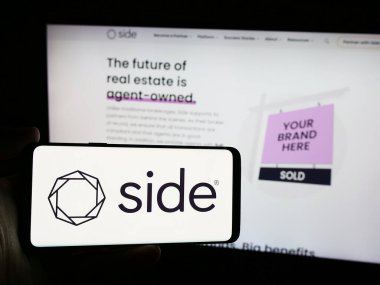 Stuttgart, Almanya - 07-12-2024: Amerikan emlak komisyonculuğu şirketi Side Real Estate Inc. 'in logosuna sahip cep telefonu sahibi kişi web sayfasının önünde. Telefon ekranına odaklan.