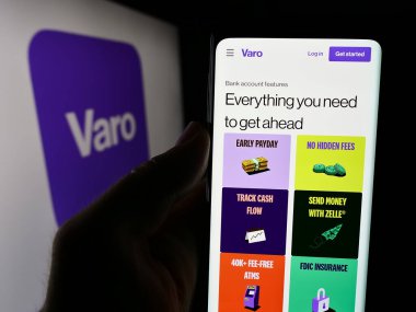 Stuttgart, Almanya - 07-12-2024: ABD 'li finans hizmetleri şirketi Varo Bank N.A.' nın internet sayfası ile cep telefonu tutan kişi Logonun önünde. Telefon ekranının merkezine odaklan.