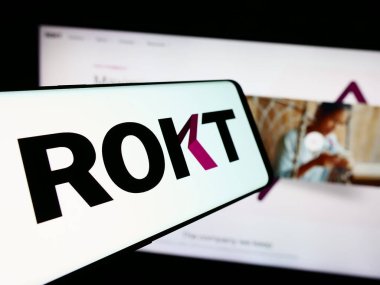 Stuttgart, Almanya - 07-14-2024: E-ticaret teknoloji şirketi Rokt Pte 'nin logosuna sahip cep telefonu. Ltd. İş sitesinin önünde. Telefon ekranının merkez soluna odaklan.