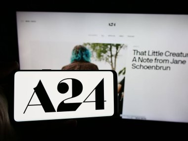 Stuttgart, Almanya - 07-14-2024: ABD 'li eğlence şirketi A24 Films LLLC' nin logosuna sahip akıllı telefon sahibi kişi web sitesi önünde. Telefon ekranına odaklan.