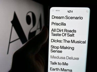 Stuttgart, Almanya - 07-14-2024: ABD 'li eğlence şirketi A24 Films LLLC' nin web sayfası ile iş logosu önünde cep telefonu tutan kişi. Telefon ekranının merkezine odaklan.