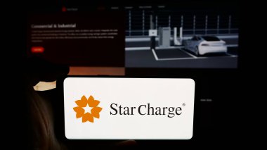 Stuttgart, Almanya - 07-14-2024: Singapurlu elektrikli araç şarj şirketi Star Charge 'ın logosunun bulunduğu cep telefonu sahibi kişi web sayfası önünde. Telefon ekranına odaklan.