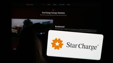 Stuttgart, Almanya - 07-14-2024: Singapurlu elektrikli araç şarj şirketi Star Charge 'ın logosuna sahip cep telefonu sahibi kişi web sayfası önünde. Telefon ekranına odaklan.