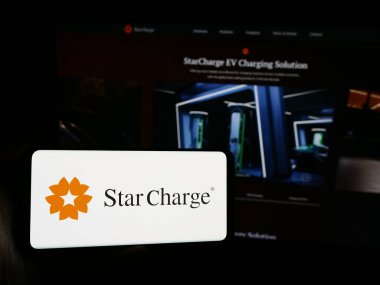 Stuttgart, Germany - 07-14-2024: Person holding smartphone with logo of Singaporean electric vehicle charging company Star Charge in front of website. Focus on phone display. clipart