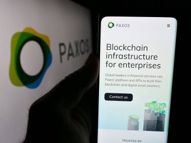 Stuttgart, Almanya - 07-14-2024: ABD 'nin blok şirketi Paxos Trust Company LLC' nin web sayfası ile logo önünde cep telefonu tutan kişi. Telefon ekranının merkezine odaklan.