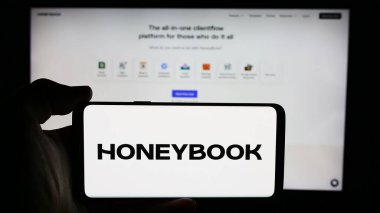 Stuttgart, Almanya - 07-14-2024: ABD 'li müşteri yönetimi şirketi HoneyBook Inc.' in logosuyla cep telefonu tutan kişi iş sayfasının önünde. Telefon ekranına odaklan.