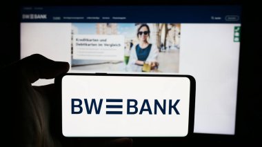 Stuttgart, Almanya - 07-15-2024: Alman Baden-Wuerttembergische Bank (BW-Bank) şirketinin logosuyla cep telefonu sahibi kişi iş sayfası önünde. Telefon ekranına odaklan.