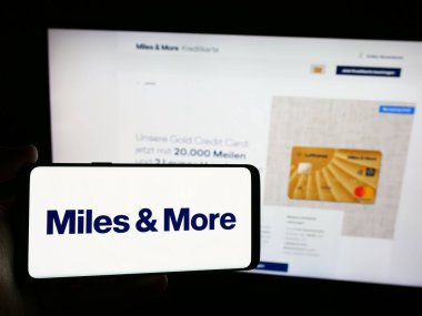 Stuttgart, Almanya - 07-15-2024: İş sayfası önünde sürekli uçuş programı Miles ve More (Lufthansa) logosu olan cep telefonu sahibi kişi. Telefon ekranına odaklan.