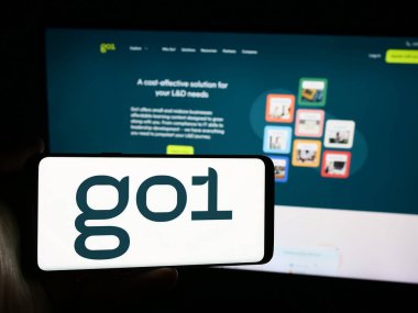 Stuttgart, Almanya - 07-15-2024: Avustralyalı online eğitim şirketi Go1 Pty 'nin logosuna sahip kişi. Ltd. Web sitesinin önünde. Telefon ekranına odaklan.