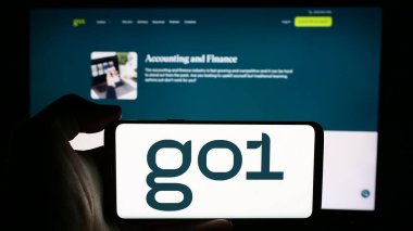 Stuttgart, Almanya - 07-15-2024: Avustralyalı online eğitim şirketi Go1 Pty 'nin logosuyla cep telefonu tutan kişi. Ltd. İş sayfasının önünde. Telefon ekranına odaklan.