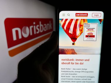 Stuttgart, Almanya - 07-15-2024: Alman finans hizmetleri şirketi Norisbank GmbH 'nin web sitesi ile logo önünde cep telefonu tutan kişi. Telefon ekranının merkezine odaklan.