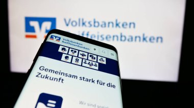 Stuttgart, Almanya - 07-15-2024: Alman bankacılık ağı Volksbanken Raiffeisenbanken 'in internet sayfalı akıllı telefon iş logosu önünde. Telefon ekranının sol üst kısmına odaklan.