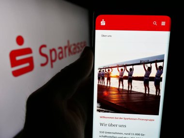 Stuttgart, Almanya - 07-15-2024: Alman finans hizmetleri kurumu Sparkasse 'ın web sitesi ile logo önünde akıllı telefon tutan kişi. Telefon ekranının merkezine odaklan.
