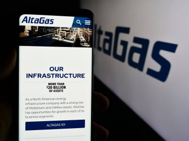 Stuttgart, Almanya - 07-16-2024: Kanadalı enerji altyapı şirketi AltaGas Ltd. 'nin internet sayfası ile logo önünde akıllı telefon tutan kişi. Telefon ekranının merkezine odaklan.