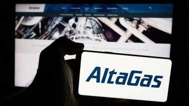 Stuttgart, Almanya - 07-16-2024: İnternet sayfasının önünde Kanadalı enerji altyapı şirketi AltaGas Ltd. 'nin logosu olan cep telefonu sahibi kişi. Telefon ekranına odaklan.