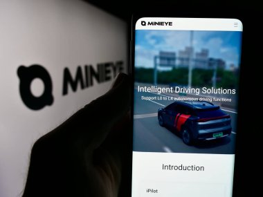 Stuttgart, Almanya - 07-16-2024: Shenzhen Youjia Innov Tech Co. Ltd. (Minieye) şirketinin internet sayfası ile logo önünde cep telefonu bulunduran kişi. Telefon ekranının merkezine odaklan.