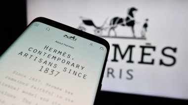 Stuttgart, Almanya - 07-17-2024: Fransız lüks şirketi Hermes International S.A. 'nın web sitesi ile birlikte iş logosu önünde cep telefonu. Telefon ekranının sol üst kısmına odaklan.