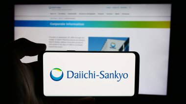 Stuttgart, Almanya - 07-17-2024: Japon şirketi Daiichi Sankyo Limited 'in logosuna sahip cep telefonu sahibi kişi iş sayfasının önünde. Telefon ekranına odaklan.