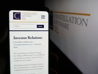 Stuttgart, Almanya - 07-17-2024: Kanadalı şirket Constellation Software Inc. 'in web sayfası ile logo önünde cep telefonu tutan kişi. Telefon ekranının merkezine odaklan.