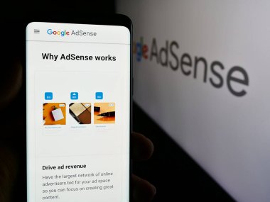 Stuttgart, Almanya - 07-17-2024: Logo önündeki Google AdSense online reklam programının web sayfası ile cep telefonu tutan kişi. Telefon ekranının merkezine odaklan.