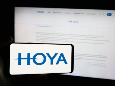 Stuttgart, Almanya - 07-19-2024: Japon hassas enstrüman şirketi Hoya Corporation 'ın logosunun bulunduğu cep telefonu web sayfasının önünde duruyor. Telefon ekranına odaklan.