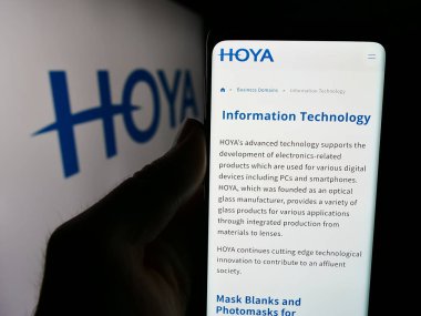 Stuttgart, Almanya - 07-19-2024: Japon hassas enstrüman şirketi Hoya Corporation 'ın logolu web sayfası ile cep telefonu tutan kişi. Telefon ekranının merkezine odaklan.