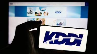 Stuttgart, Almanya - 07-19-2024: İnternet sitesi önünde Japon telekomünikasyon şirketi KDDI Corporation 'ın logosuna sahip kişi. Telefon ekranına odaklan.