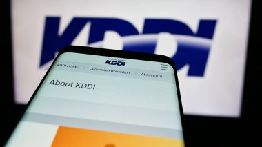 Stuttgart, Almanya - 07-19-2024: Japon telekomünikasyon şirketi KDDI Corporation 'ın internet sitesi ile ticaret logosu önünde akıllı telefon. Telefon ekranının sol üst kısmına odaklan.