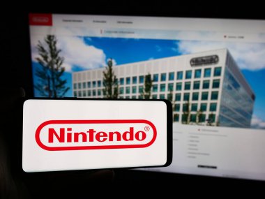 Stuttgart, Almanya - 07-19-2024: Japon video oyunu şirketi Nintendo Co. Ltd. nin logosuna sahip akıllı telefon sahibi kişi web sitesinin önünde. Telefon ekranına odaklan.